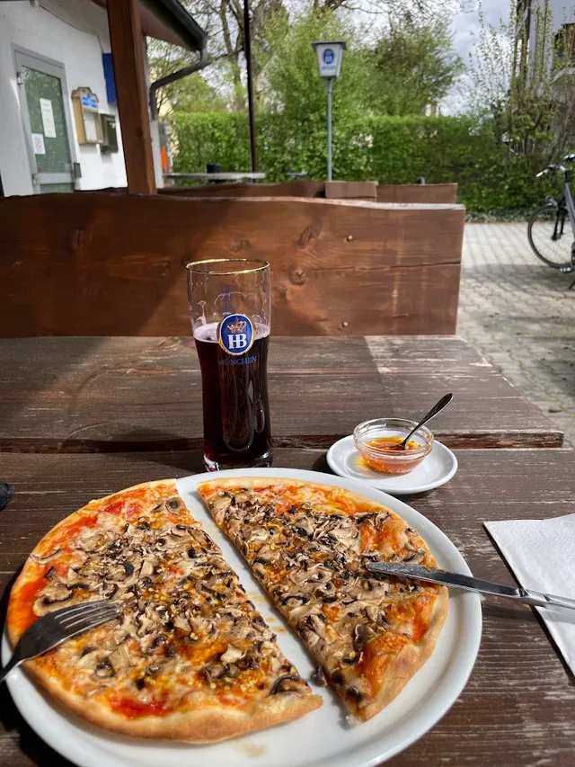 Pizza und ein Bier auf dem Holztisch im Biergarten