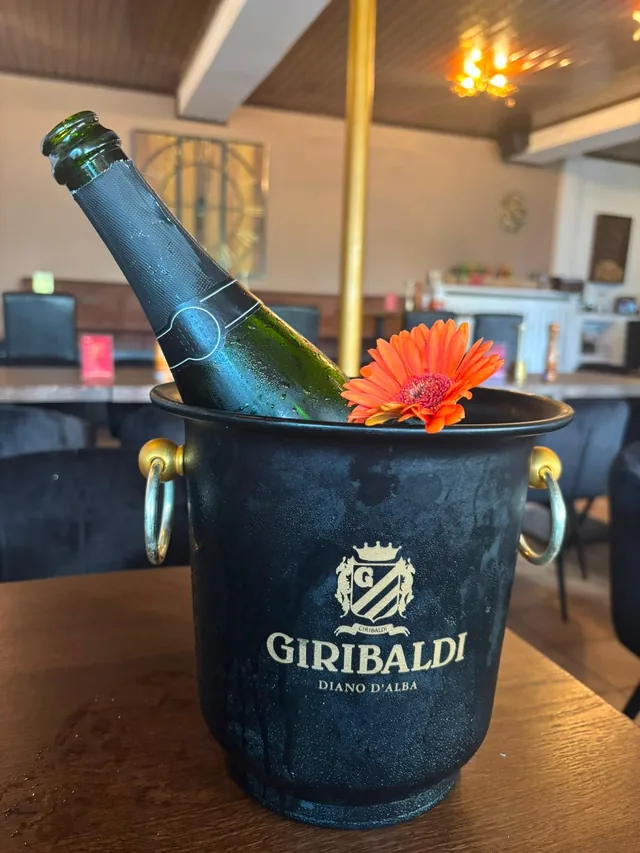 Flasche im Sektkühler mit einer Gerbera im warm beleuchteten Hauptraum