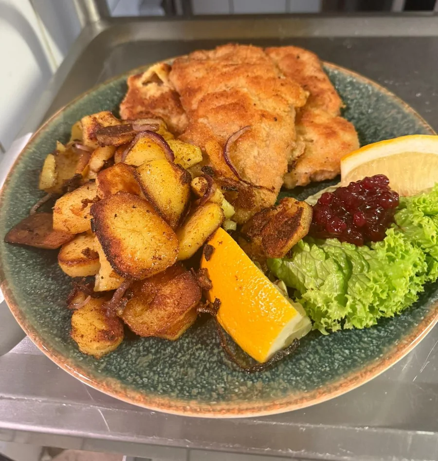 Gebackenes mit Bratkartoffeln und Salat auf türkisem Teller